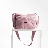 Bandolera color rosa con tres bolsillos frontales con cierre y correa larga regulable.
