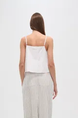 Musculosa blanca de algodón con breteles finos, bordado calado y botones frontales.
