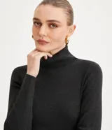 Suéter de punto color blanco, con cuello alto estructurado, manga larga y efecto texturizado.