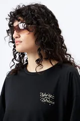 Remera blanca de corte holgado con mangas cortas y cuello redondo. Estampado pequeño en el frente con la frase "Spritz and Shine" en verde.