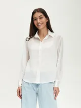 Camisa blanca de mangas largas abullonadas con puños abotonados y cuello clásico.