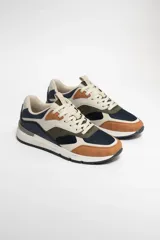 Zapatillas deportivas acordonadas con capellada de cuero sintético color beige, detalles en azul marino, verde oliva y marrón. Suela blanca con base negra.