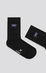 Medias negras con diseño de un monstruo de videojuego pixelado en color lila.