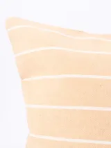 Funda de almohadón rectangular color beige con rayas horizontales blancas.