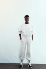 Zapatillas deportivas de mujer con combinación de materiales en negro, blanco y marrón. Cierre con cordones y suela en contraste color caramelo.