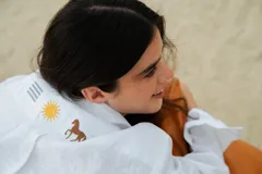 Camisa negra de lino con cuello clásico, manga larga y cierre frontal con botones. Presenta un bordado con un caballito, un sol y la bandera de Uruguay en el frente.