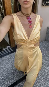 Vestido largo color durazno con escote pronunciado en V y aberturas laterales en la cintura. Presenta un drapeado frontal y falda con tajo lateral.