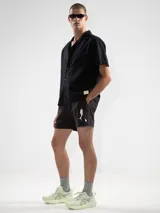 Short de baño negro con bordado de enredadera blanca en la pierna izquierda. Cuenta con cintura elástica con cordón ajustable, bolsillos laterales y bolsillo trasero con cierre. Incluye suspensor de malla fina hipoalergénico.