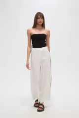 Pantalón blanco de viscosa, corte ancho y tiro alto, con detalle de bordado calado negro en los laterales.