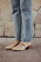 Zapatos de charol color beige con taco bloque de madera y tira sobre el empeine con hebilla dorada.