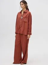 Pantalón de vestir color ladrillo, de corte holgado y tiro alto, con caída recta y detalle de diseño al costado.