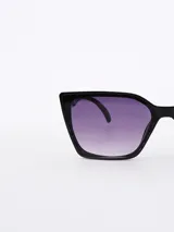 Lentes de sol negros con forma cat-eye y lentes degradadas en tonos violeta.