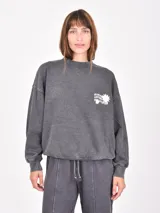 Buzo de manga larga color gris oscuro con efecto lavado (acid wash) y puños y ruedo ajustados. Presenta un pequeño estampado blanco en el pecho con un sol y texto.