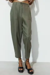 Pantalón capri color verde militar confeccionado en lino, de tiro medio, con bolsillos laterales y traseros. Cierre frontal con cremallera y botón.