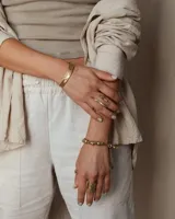 Pulsera tipo esclava abierta, con acabado rústico y textura irregular, en tono plateado. Se vende por unidad.