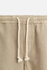 Bermuda color beige de denim de algodón, corte relaxed fit, con cintura elástica ajustable con cordón, bolsillos frontales y traseros.