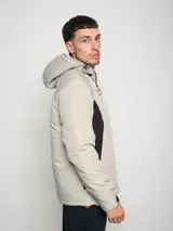 Campera corta de abrigo Umbro Crafted Pro, color negro con paneles laterales en gris. Presenta capucha con cordón ajustable, cierre frontal completo y logo de la marca bordado en el pecho.