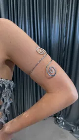 Brazalete plateado para el brazo con diseño de espiral en los extremos.