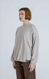 Sweater beige de corte holgado, cuello redondo y mangas largas con puños elásticos.