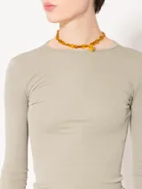 Remera rosa de punto con textura suave, mangas largas, escote redondo y espalda amplia y abierta.