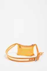 Minibolso amarillo de tejido de red con detalles en piel y charms metálicos. Presenta etiqueta logotipada BIMBA Y LOLA y cierre ajustable de cordón, con acabados metálicos plateados.