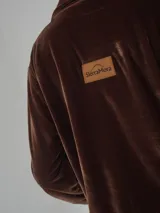 Camisa roja de terciopelo con cuello clásico, botones frontales y mangas largas con puños abotonados. Tiene dos bolsillos de parche en el pecho.