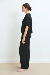 Conjunto de pijama negro, compuesto por una remera de manga corta con detalle de encaje en los puños y un pantalón largo de corte recto.