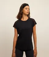 Top deportivo negro de poliamida, con escote redondo y breteles medianos. Presenta detalle contrastante color naranja en el bajo y en los bordes de las mangas.