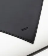 Bolso satchel mediano bicolor, negro en la parte superior y blanco en la inferior, con detalles metálicos dorados en las asas. Incluye correa larga desmontable y cierre de cremallera.