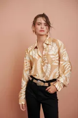 Camisa beige con estampado de hojas blancas, de corte clásico y manga larga.