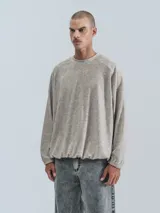 Sweater beige de corte holgado, cuello redondo y mangas largas con puños elásticos.