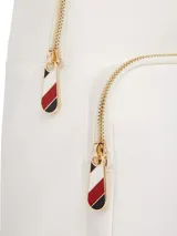 Mochila blanca de nailon con diseño curvo, cierre de cremallera, asa superior y correas ajustables. Tiene un compartimento principal, un bolsillo interior abierto y un bolsillo exterior con cremallera. Incluye el logo de Tommy Hilfiger en dorado en el frente.