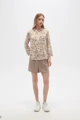 Camisa de viscosa con estampado floral en tonos azul, beige y blanco. Tiene cuello mao, mangas largas y bolsillos en el pecho.