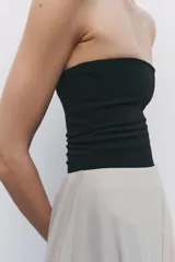 Body bandeau color verde oliva confeccionado en tejido elástico, con escote recto y hombros descubiertos. Cierre inferior con botones a presión.