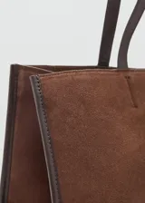 Bolso tipo shopper de piel de serraje color marrón, con diseño de paneles cosidos en el frente y bordes ribeteados en cuero liso oscuro. Posee dos asas de hombro de cuero liso oscuro y cierre de botón magnético.