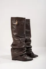 Botas de caña alta color marrón chocolate, de cuero vegano, con punta fina y detalle de candado dorado en la parte superior.