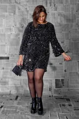 Vestido corto negro con lentejuelas plateadas, de mangas largas y escote redondo.