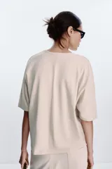 Camiseta color beige de corte amplio, cuello redondo y mangas cortas.