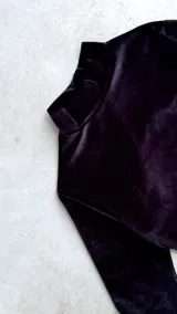 Body de terciopelo marrón con estampado de piel de serpiente, cuello alto, mangas largas con orificio para el pulgar y espalda descubierta.