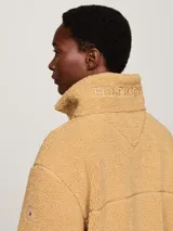 Campera color beige de tejido polar de peluche, con cuello alto, cierre de cremallera, bolsillos laterales y puños elásticos.