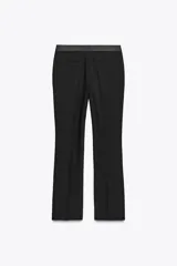 Pantalón negro de tiro alto con corte flare y cinturilla combinada a tono. Presenta bolsillos laterales y falsos bolsillos de vivo en la espalda.