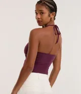 Top cropped de algodón color amarillo pálido, con escote en V pronunciado y tirantes finos que se atan en la nuca (estilo halter). El tejido es acanalado.