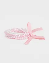Set de cinco pulseras elásticas de perlas blancas con cinta de raso color crema.