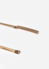 Cinto elastizado dorado con placa rectangular metálica.