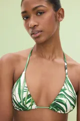 Top de bikini triangular blanco con estampado de hojas de palmera verdes y tirantes finos para atar al cuello y a la espalda.
