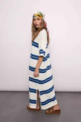 Vestido largo tejido a rayas horizontales azules y beige sobre fondo blanco, con mangas cortas y tajos laterales.