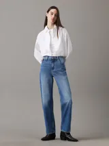 Camisa blanca de algodón Oxford, corte relaxed, cuello en punta, manga larga con puños abotonados y bajo redondeado.