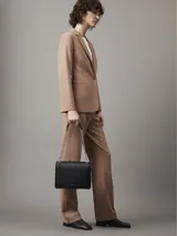 Cartera Calvin Klein negra con diseño acolchado, correa de cadena plateada y logo de la marca en el frente.