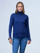 Polera de punto fino marca Nienty, color blanco, con cuello alto volcado y mangas largas con detalle de tajo en los puños.