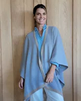 Ruana negra de tejido de punto con una estrella grande color beige en la espalda y borde inferior con franja beige.